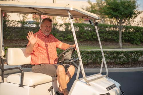 Member of Team Mainstreet driving golf cart during Clermont's 2nd anniversary celebration