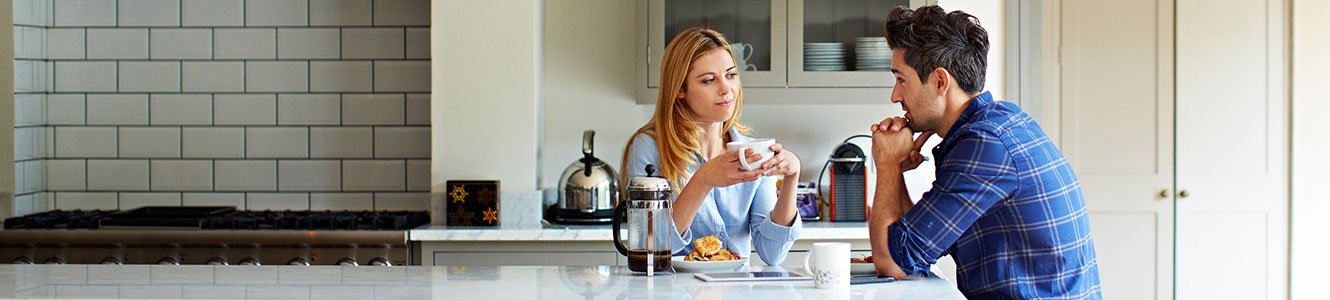 Young couple drinking coffee in their kitchen.