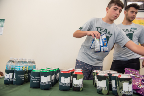 Sodas in Mainstreet Community Bank coozies sitting on a table as two young men line up chips at DeLand High School
