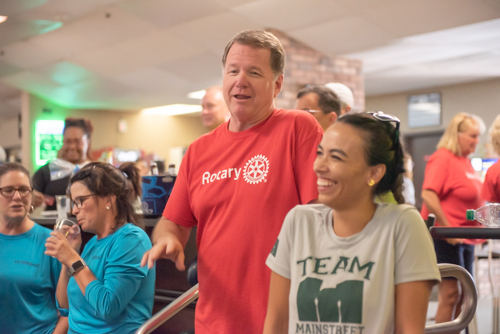 A man and woman laugh while other people chat in background at Bowling for Literacy event in DeLand
