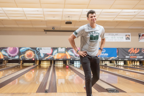 Man walking away from bowling lane with hands on hips