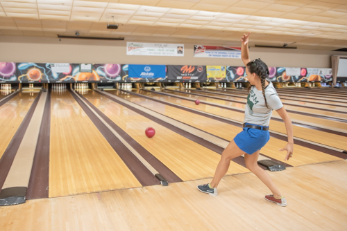 A woman bowls in a comical way during Bowling for Literacy event.