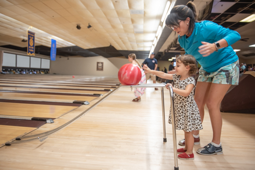 A woman helps a little girl bowl during Bowling for Literacy event in DeLand FL