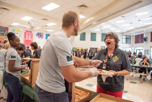A teacher excitedly grabs a man who is a former student while serving lunch for the staff of DeLand High School